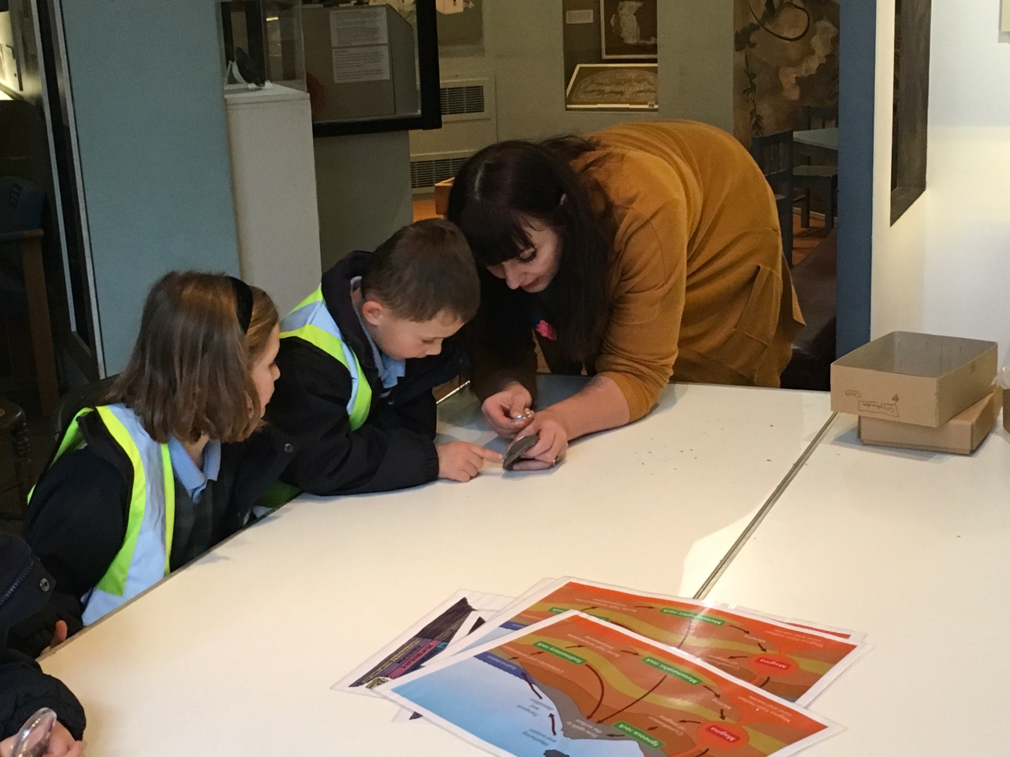 A pupil looks at a fossil through a magnifying glass